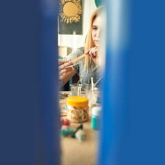Young caucasian female creating art with paintbrush in colorful studio.