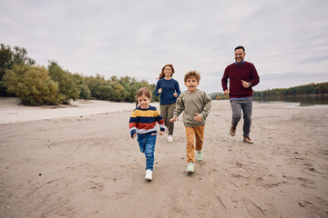 Happy family running while having fun in nature in autumn.
