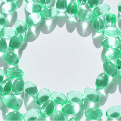 Shiny green gel capsules arranged in circular pattern on white background.