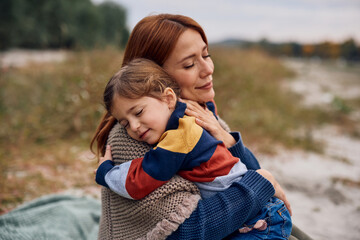 Affectionate mother and daughter spending time together in nature in autumn.