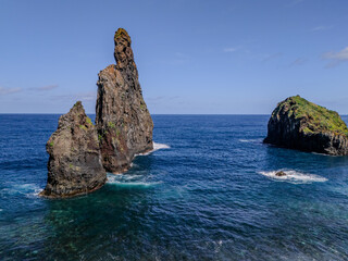 Naklejka premium Dramatic sea stack rising from the Atlantic Ocean near the lush green cliffs of Ribeira da Janela, Madeira. 