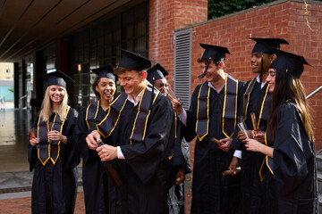 Diverse students celebrating university graduation with champagne