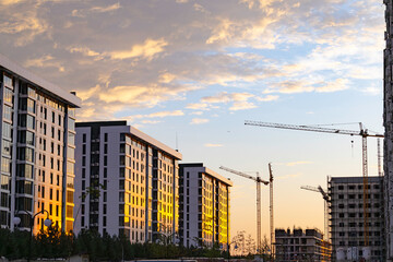 Construction of a new residential area using high-rise cranes at sunset.