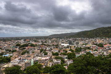 Panoramic view of Port Louis, the capital city of Mauritius, with a dramatic mountain range in the background under moody skies. This urban landscape highlights the contrast 