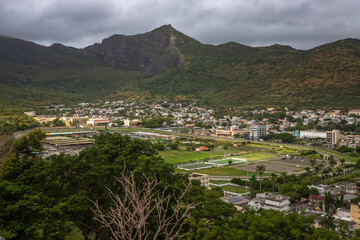 Panoramic view of Port Louis, the capital city of Mauritius, with a dramatic mountain range in the background under moody skies. This urban landscape highlights the contrast 
