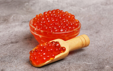 a bowl of red caviar and a scoop