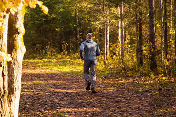 Fototapeta premium A man runs through a sunny autumn park