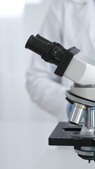Microscope is on a table, ready for innovative medical research in a sterile laboratory environment. In the background, a scientist analyzes the data obtained. Medicine and science