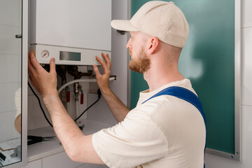 Repairman performs maintenance on gas boiler in modern bathroom setting