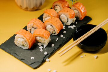 Delicious sushi rolls served on a black slate plate with soy sauce and chopsticks