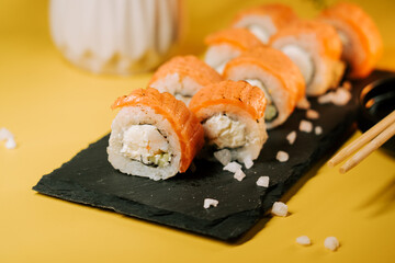 Sushi rolls with salmon and cream cheese served on slate plate with soy sauce