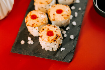 Unique sushi rolls with cheese and sauce served on slate board