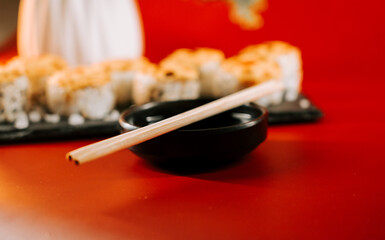 Delicious sushi setup with black bowl and chopsticks on vibrant red table