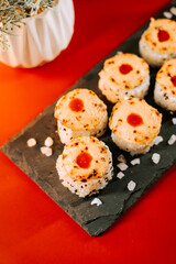 Delicious sushi rolls with a glossy topping on a black slate plate