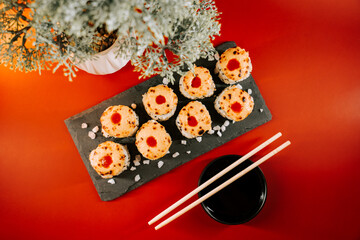 Sushi rolls topped with colorful toppings served on a black stone plate