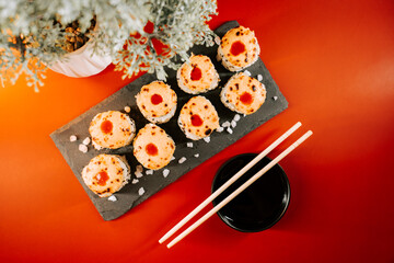 Delicious sushi rolls served on a black slate plate with chopsticks and soy sauce