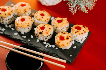 Deliciously prepared sushi rolls served on a black stone platter with chopsticks