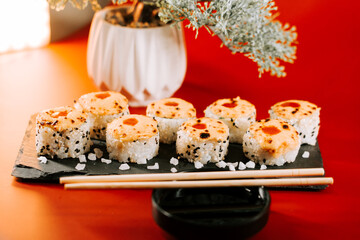 Sushi rolls with a creamy topping served on a slate plate in a cozy dining setting