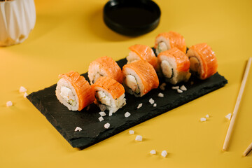 Fresh sushi rolls arranged on a serving platter with a vibrant yellow background
