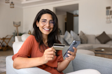 Happy young Hispanic woman using mobile phone and credit card