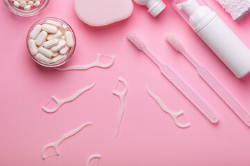 White toothbrushes and nutritional supplements, vitamins and minerals, dental floss, toothpaste from above on pink background. Oral care, gum and teeth health. Morning routine and health care.