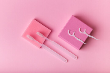 White toothbrushes, dental floss from above on pink background. Oral care, gum and teeth health. Morning routine and health care.