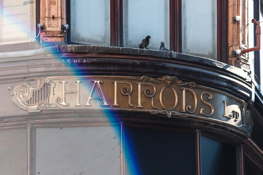 London, United Kingdom - August 13, 2022: Vintage Harrods sign with golden lettering on the historic facade of the famous luxury department store in Knightsbridge, London