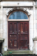 Cardiff, Wales - August 14, 2022: Old wooden door with chain and padlock on a historic stone building facade