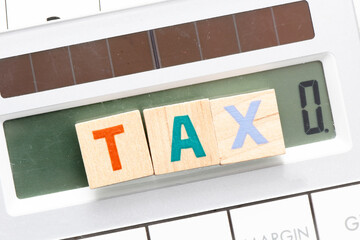 TAX word arranged with wooden letters on the calculator screen.