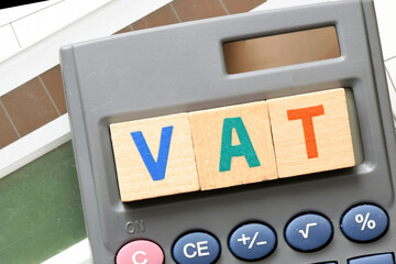 VAT word arranged with wooden letters on the calculator screen. Settlement VAT in Poland.
