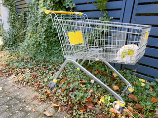Abandoned shopping cart in empty urban area, symbol of consumerism, waste and modern lifestyle