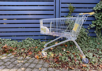 Abandoned shopping cart in empty urban area, symbol of consumerism, waste and modern lifestyle