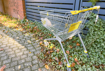Abandoned shopping cart in empty urban area, symbol of consumerism, waste and modern lifestyle