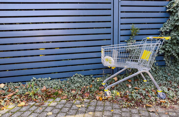 Abandoned shopping cart in empty urban area, symbol of consumerism, waste and modern lifestyle