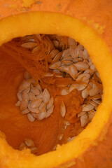 Close-up view of hollowed pumpkin interior showcasing orange flesh and scattered seeds, highlighting the natural textures and vibrant colors of autumn harvest