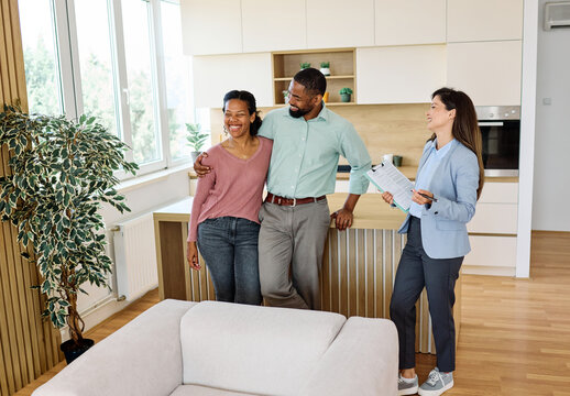 Female Real Estate Agent Selling And Showing The Modern Apartment kitchen To His Young Clients, young couple That Are Standing Next To her In The Fancy Apartment - Powered by Adobe