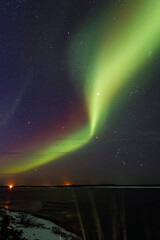 Stunning display of northern lights illuminating the night sky over a tranquil lake, with vibrant green and purple hues creating a mesmerizing natural phenomenon