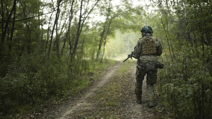 Camouflaged army soldier with AR15 carbine on a war recon mission. Traversing the rough terrain. Military recon
