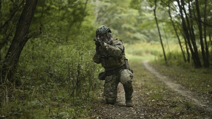 Camouflaged army soldier with AR15 carbine on a recon mission. Sitting still and aiming. Military recon