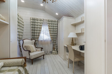 A bright and inviting room showcases a stylish armchair next to a desk. Soft curtains frame the window, while the wooden floor adds warmth, creating a serene atmosphere for relaxation or work.