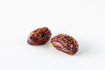 Two single whole organic medjool dates isolated against a white background.
