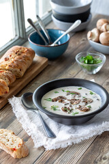 A bowl of cream of mushroom soup served with crusty bread, ready for eating.