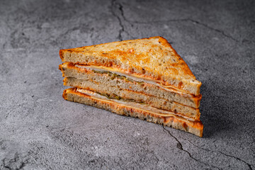 Layered grilled turkey and cheese sandwich with golden toast, served on a rustic stone backdrop