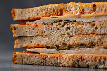 Layered grilled turkey and cheese sandwich with golden toast, served on a rustic stone backdrop
