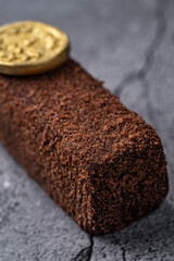 Rich Chocolate Fudge Cubes with a Gold Coin Decoration on a Textured Stone Background