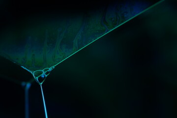 Colourful rainbow reflection of liquid in macro, white colors, surrealistic background, fantastic smooth movement, water surface, interference pattern, glowing film, chemical experiment