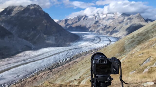Professional camera on a tripod filming glacier in Swiss alps, Aletsch glacier