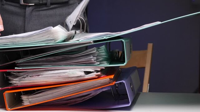 Person looking through stack of overflowing office binders