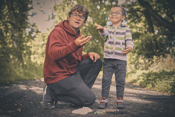 Adult man and his son training classic marbles outdoor on pathway in nature