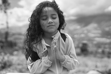 Young girl praying with hands together and closed eyes. Children's Week